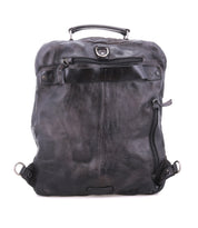 The Bed|Stü Lafe backpack is shown in black leather with a top handle, front zipper pocket, and metal hardware against a white background. This versatile bag doubles as a sleek 17-inch laptop backpack, making it an ideal choice for daily use and travel.