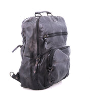 The Bed|Stü Lafe is a black leather backpack featuring three zippered compartments, a top handle, and adjustable straps, designed as an anti-theft travel bag to securely carry your essentials; shown against a plain white background.