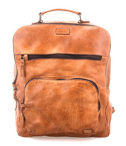 The Bed|Stü Lafe brown leather backpack, featuring two zippered front pockets and a top handle for easy carrying, is expertly designed as an anti-theft travel bag and is shown against a white background.