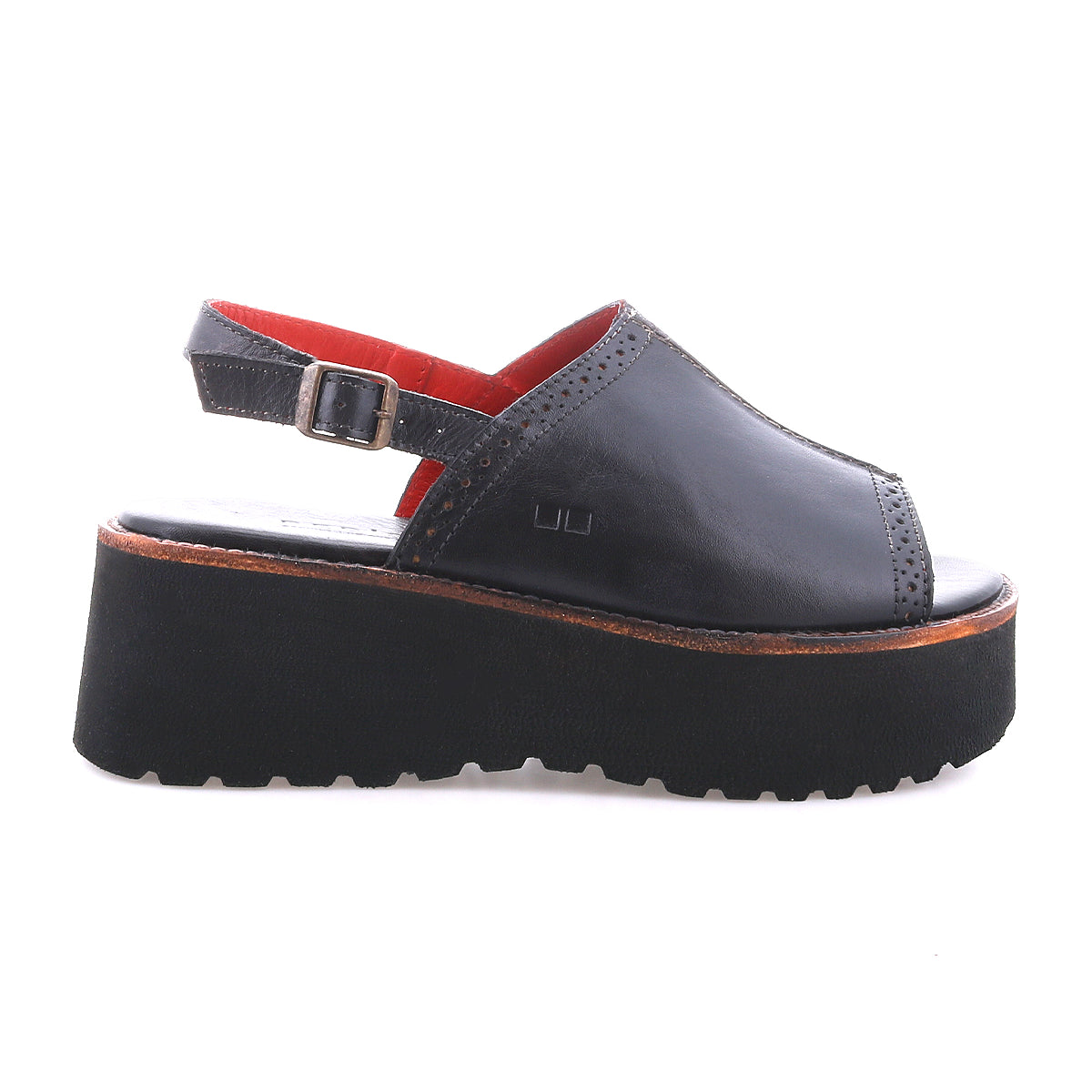 The Bed|Stü Library is a black platform sandal featuring an open toe, adjustable ankle strap, and a thick black sole. Made with leather uppers highlighted by subtle stitching details, this sandal embodies the essence of ‘90s retro style. Shown against a white background.