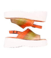 A pair of Bed|Stü Library platform sandals, featuring white soles and orange-to-green gradient leather uppers, are displayed side by side on a white background, capturing a retro '90s-inspired footwear aesthetic.