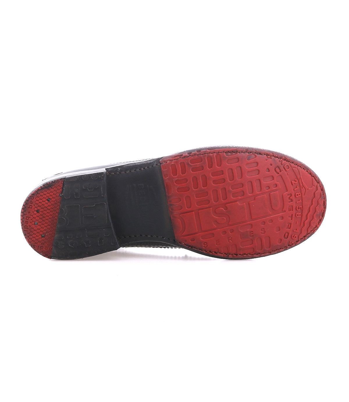 The image shows the bottom of the Bed|Stü Lita K II shoe, featuring a textured sole with embossed patterns across its surface. The sole is primarily red with a black section near the heel, complementing the classic derby style of this design.