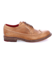 Introducing the Bed|Stü Lita K II: a tan leather classic derby brogue dress shoe with a wingtip toe and intricate decorative perforations, featuring dark laces, a brown sole, and a striking red inner lining, shown in side profile against a white background.