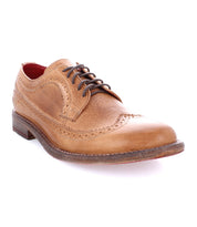 The Bed|Stü Lita K II is a light brown leather classic derby dress shoe with brogue detailing, featuring decorative perforations, a wingtip toe, dark brown laces, and a low stacked heel, shown on a white background.
