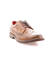 The Bed|Stü Lita K II, a single brown leather wingtip oxford shoe with laces, featuring classic brogue detailing and a distinctive wingtip toe, is displayed on a white background.