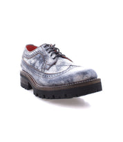 The Bed|Stü Lita K III is shown as a single gray leather dress shoe with brogue detailing, black laces, and a thick, rugged sole that evokes the charm of a vintage-inspired design, displayed on a white background.