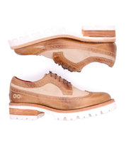 Two Lita K III brogue dress shoes by Bed|Stü, featuring tan and beige canvas and leather uppers with thick white lug soles, are positioned parallel—one above the other—on a white background.