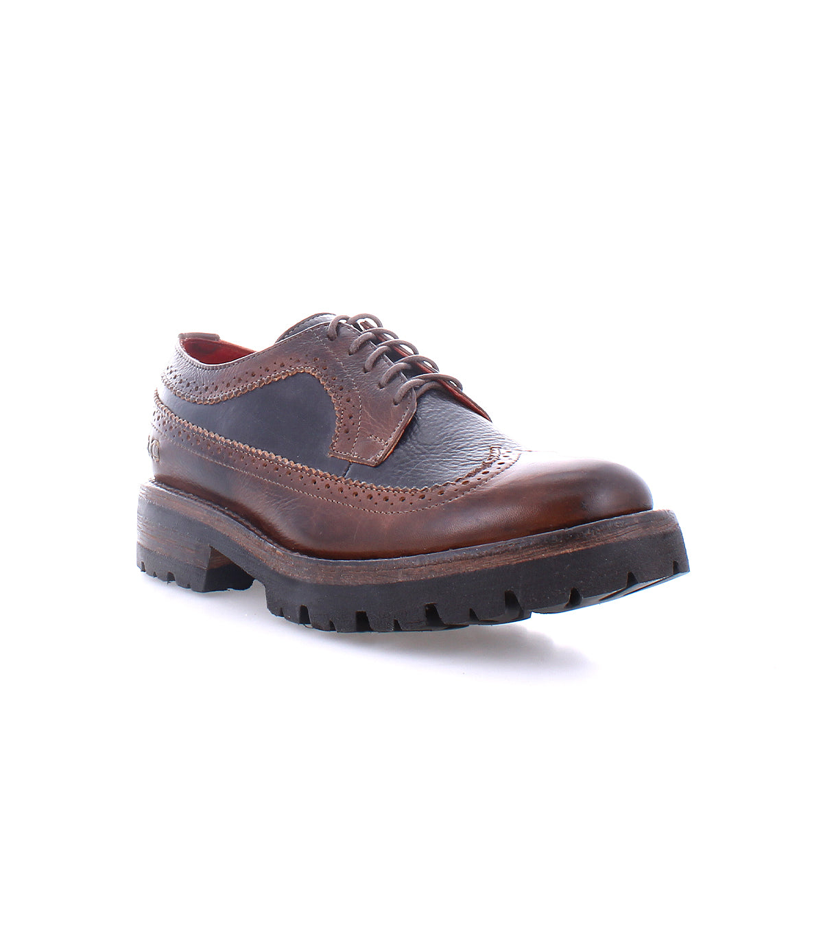 The Bed|Stü Lita K III is pictured against a white background, showcasing its brown leather brogue design with dark textured canvas and leather panels, red lining, decorative stitching, and a thick, rugged rubber sole.
