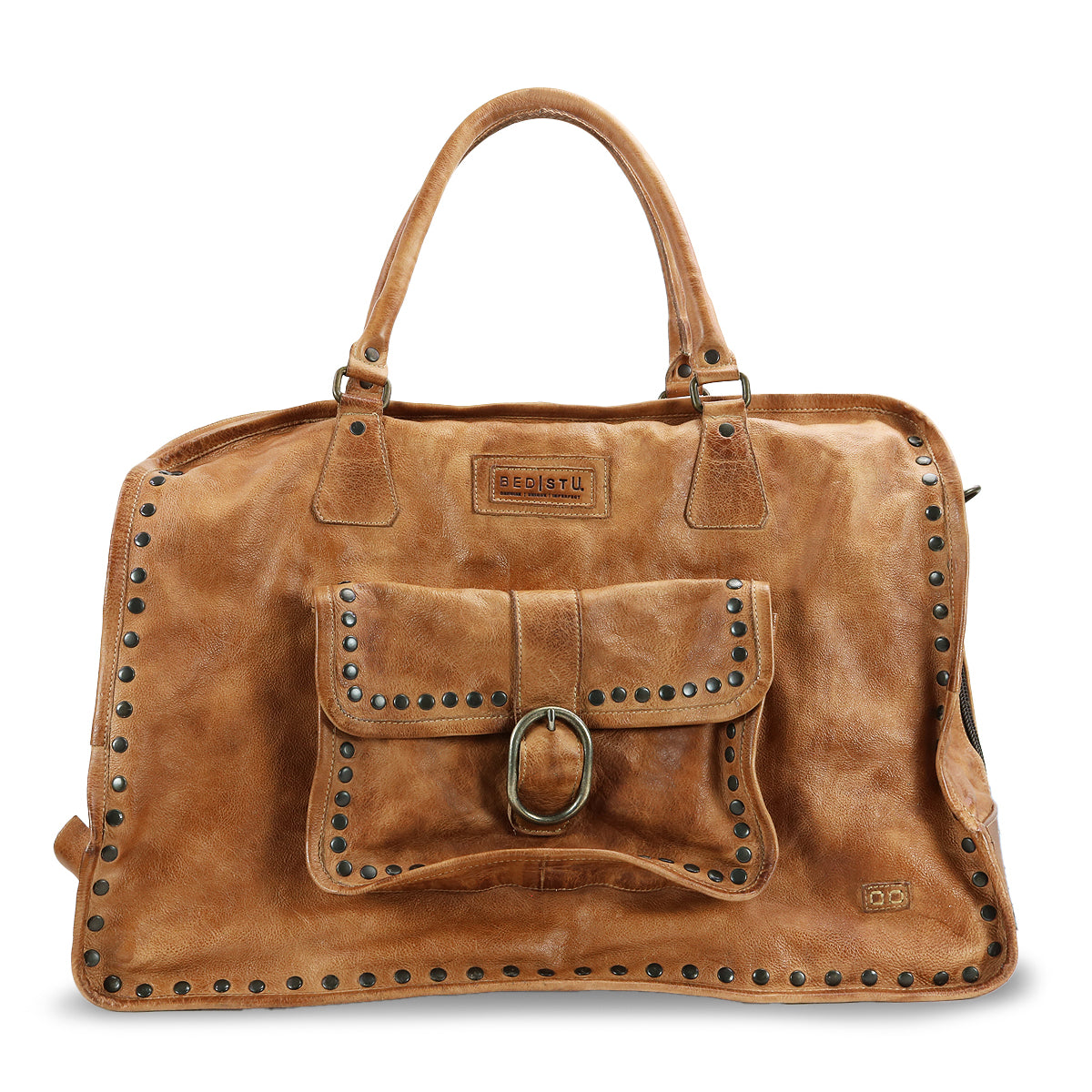 The Loaf by Bed|Stü is a brown leather handbag with double handles, a front pocket accented by a buckle, and metal stud detailing along the edges and pocket—making it a stylish travel bag for your next getaway.