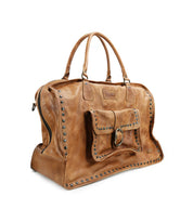 Loaf by Bed|Stü—a large brown leather duffle bag embellished with metal studs, double handles, and a front pocket with buckle closure—presented on a white background; the perfect travel companion for stylish journeys.