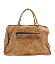 The Bed|Stü Loaf is a large tan leather duffel bag featuring two handles and a front zippered pocket, displayed against a plain white background—a versatile travel companion that’s perfect as a stylish carry-on.