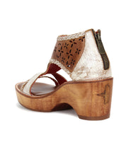 Introducing Locket by Bed|Stü—a heeled sandal featuring a sculpted wooden heel, metallic crackle finish, laser-cut floral leather upper, cushioned footbed for comfort, back zipper, and ankle strap.