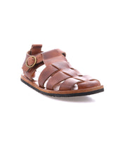The Bed|Stü Lone is a brown leather sandal featuring a closed toe, open sides, and an antique brass buckle closure on the side, shown on a white background.