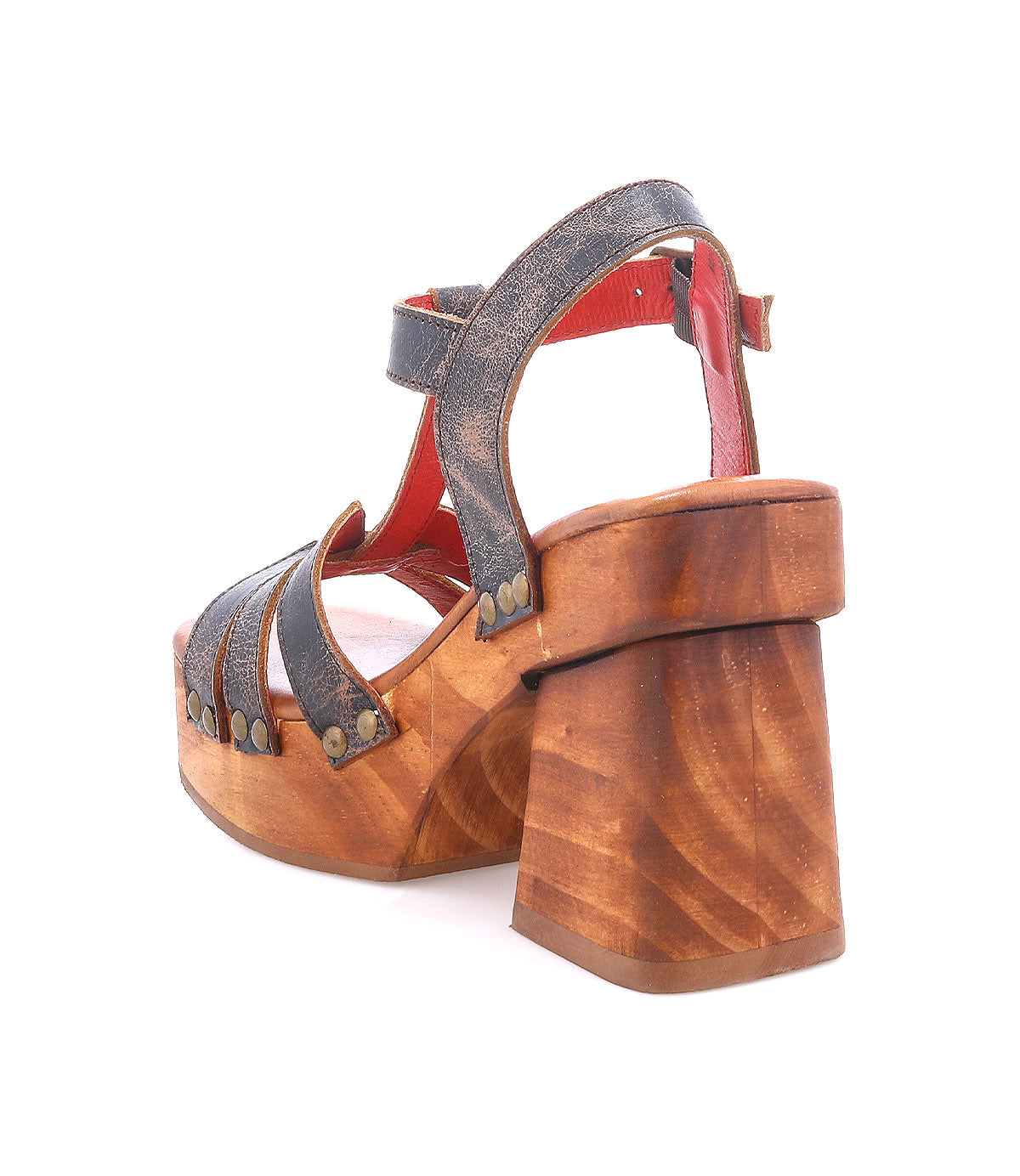 The Lyxon by Bed|Stü is a high-heeled, open-toe sandal with a thick wooden platform heel, dark riveted straps, and a red lining, displayed from a rear side angle against a white background.