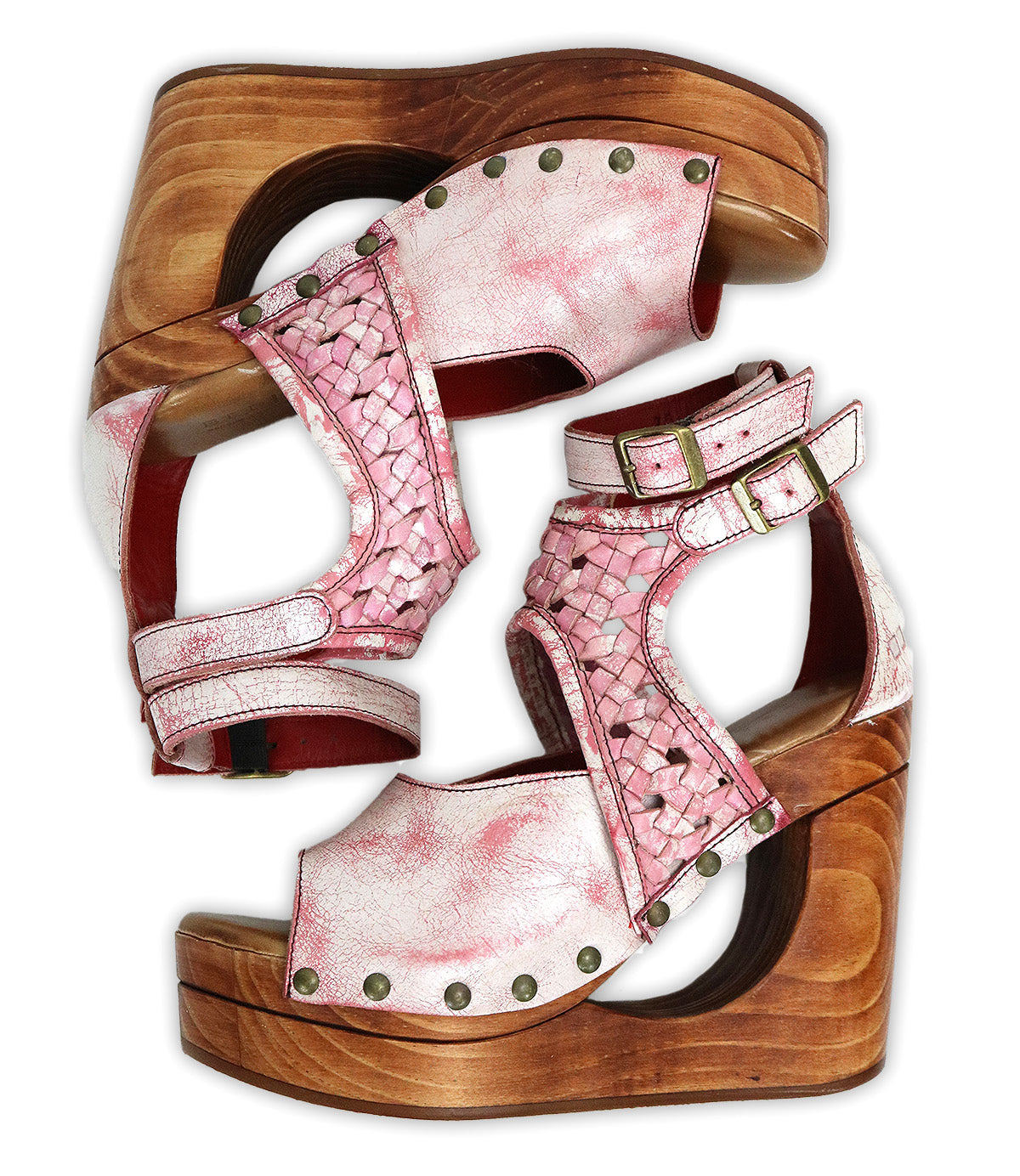 A pair of Bed|Stü Magic sandals in pink, displayed side by side on a white background, features a handwoven leather upper with a peep-toe design, sculpted wooden wedge heels, metal studs, and ankle straps.