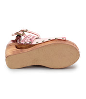 The Bed|Stü Magic sandal is shown from the sole side, highlighting its pink leather upper, sculpted wooden wedge platform heel, metal studs, buckle strap, and chic peep-toe design.