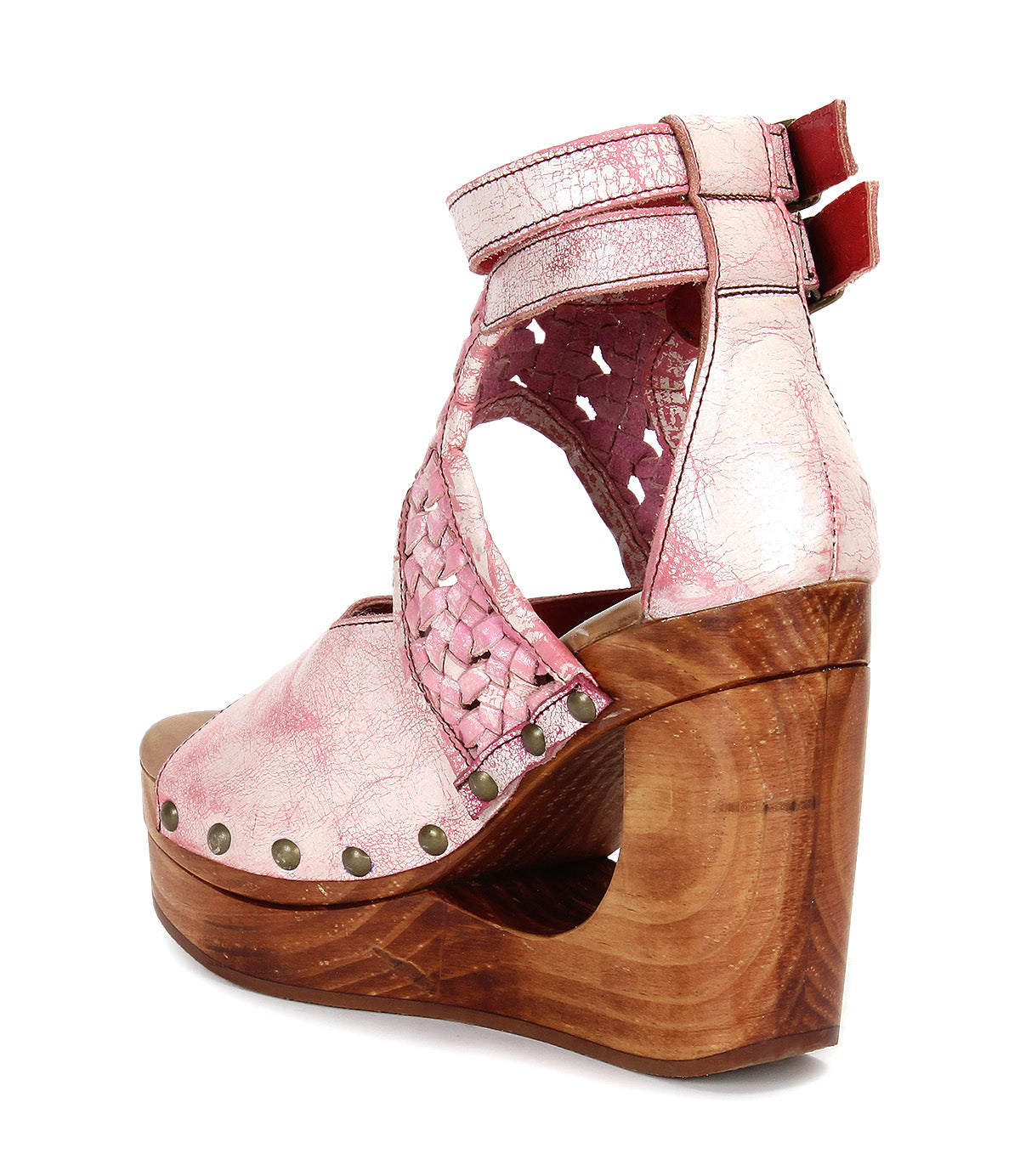 Introducing the Magic by Bed|Stü—a pink leather wedge sandal featuring a handwoven leather upper, metallic studs, a sculpted wooden wedge platform heel, and double ankle straps with red accents at the back.