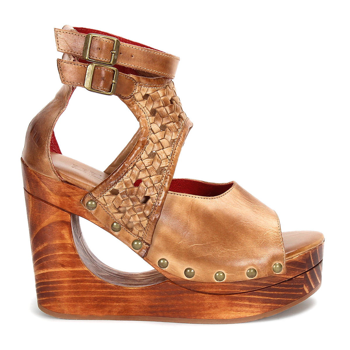 Introducing Bed|Stü’s Magic wedge sandal—a tan leather shoe featuring a handwoven upper with intricate woven details, chic peep-toe styling, adjustable ankle straps with buckles, metal stud embellishments, and a sculpted wooden platform wedge heel accentuated by bold cut-out designs.