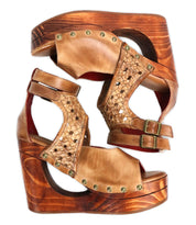 A pair of Bed|Stü Magic brown leather wedge sandals, featuring a handwoven leather upper, sculpted wooden wedge, brass stud detailing, ankle straps with buckle closures, and a refined peep-toe design, are placed side by side facing opposite directions.