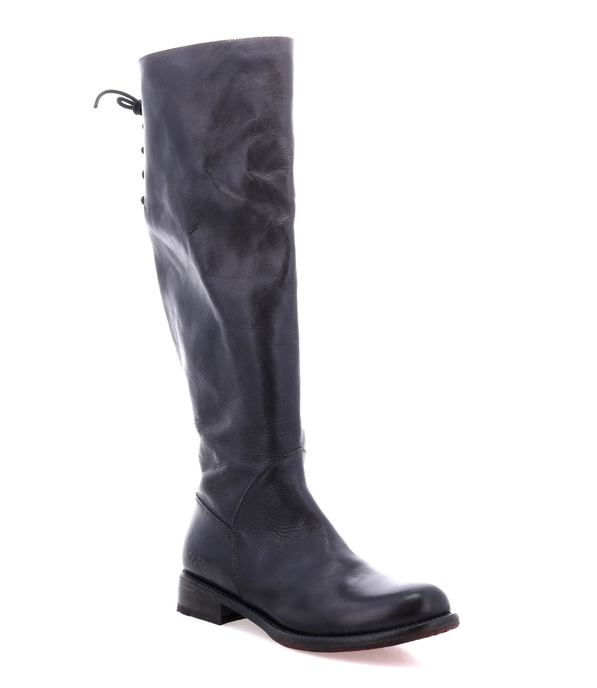 The Bed|Stü Manchester boot, crafted from sleek black leather, showcases a tall silhouette with an elegant back lacing detail and a comfortable flat heel. Presented against a white background, this modern classic effortlessly blends style and comfort for any occasion.