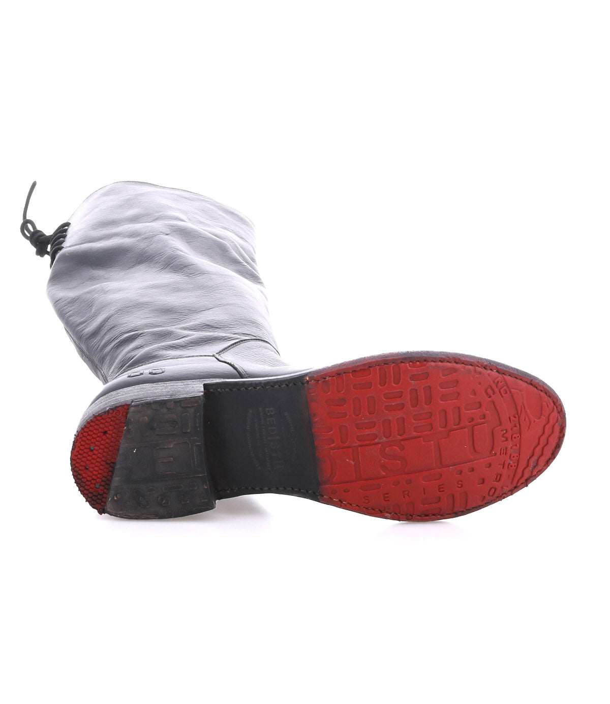 Introducing the Manchester boot by Bed|Stü: This modern classic in black leather is pictured lying on its side, highlighting a red, textured sole with worn tread patterns and distinct Bed|Stü branding near the heel. Featuring a comfortable flat heel, it’s ideal for effortless everyday wear.