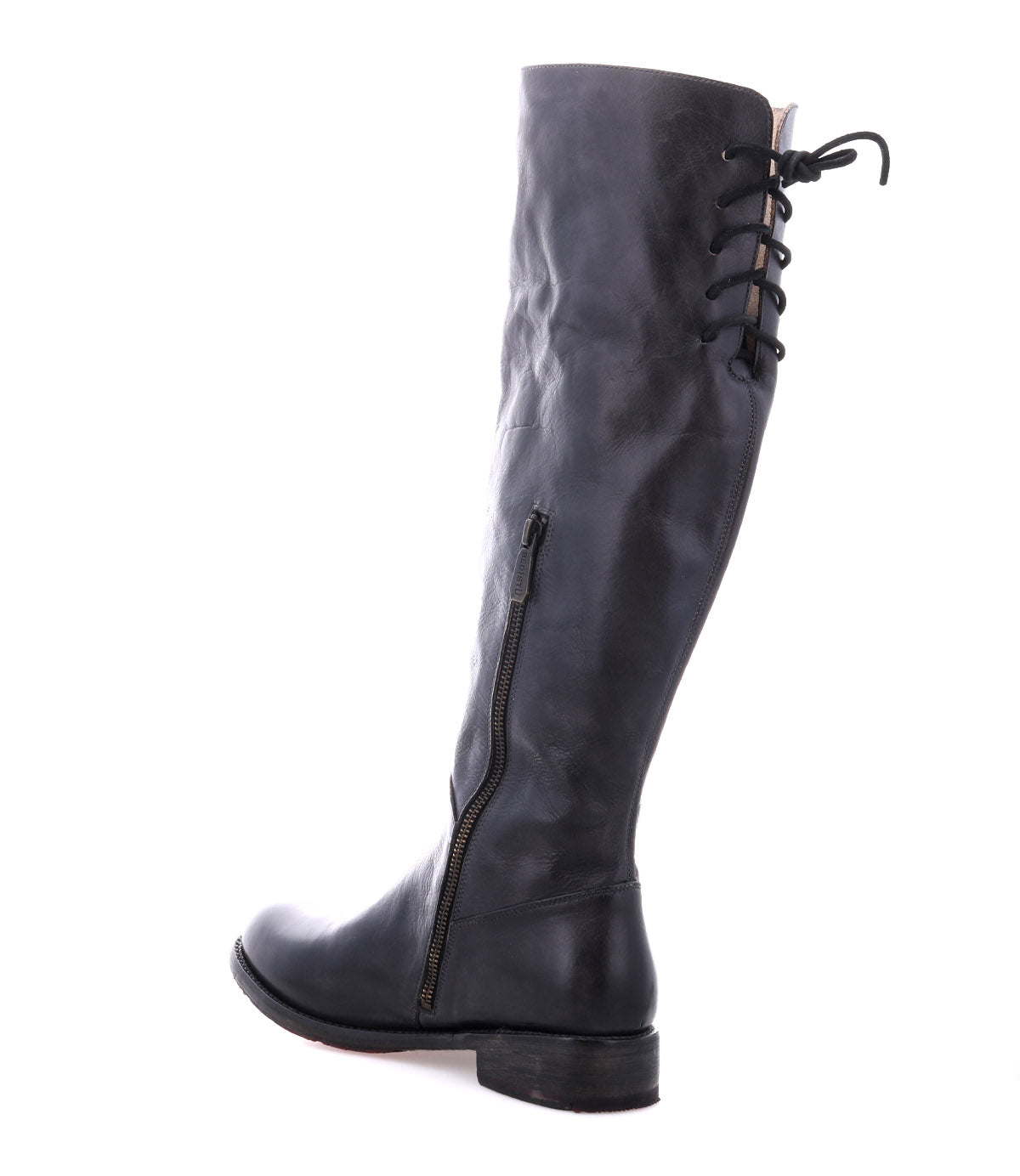 The Bed|Stü Manchester is a black knee-high leather boot featuring a low, comfortable flat heel, a side zipper, and lace-up detailing at the back of the calf. This modern classic boot is photographed against a white background.