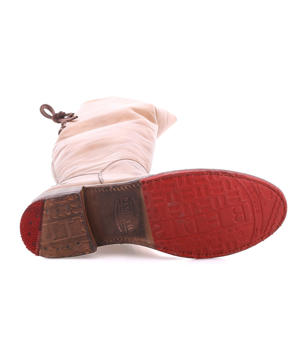 The Bed|Stü Manchester boot in light beige leather is pictured lying on its side, displaying a textured red rubber outsole and a brown block heel.