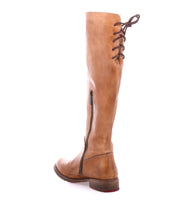 The Bed|Stü Manchester is a tan tall leather boot with a comfortable flat heel, side zipper, and brown lace-up detail at the back, photographed on a white background—a modern classic perfect for any occasion.