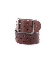 The Bed|Stü Mccoy is a brown leather belt with a durable metal buckle and multiple round holes for a customizable fit, featuring a sturdy leather strap coiled on a white background.