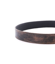 A close-up of the Bed|Stü Meander belt, crafted from rugged brown leather with a worn texture, displayed in a circular shape on a white background.