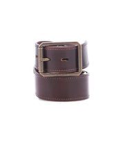 The Meander belt by Bed|Stü is crafted from brown distressed leather with prominent stitching and showcases a rectangular antique metal buckle. The brand’s name, "Bed|Stü," is embossed near the buckle on the front, emphasizing the rugged authenticity of its craftsmanship. Pictured against a white background.