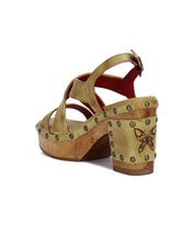 Introducing the Mediation sandal by Bed|Stü—a tan strappy heeled slingback crafted from soft leather straps. This standout style features a chunky wooden heel adorned with a butterfly design, metal studs for added flair, and a secure buckle ankle strap. Designed for all-day comfort with a cushioned insole.
