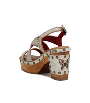 Introducing Mediation by Bed|Stü: a beige slingback sandal with a wooden block heel, decorative studs, crisscross leather straps, and a butterfly design accenting the back of the heel.