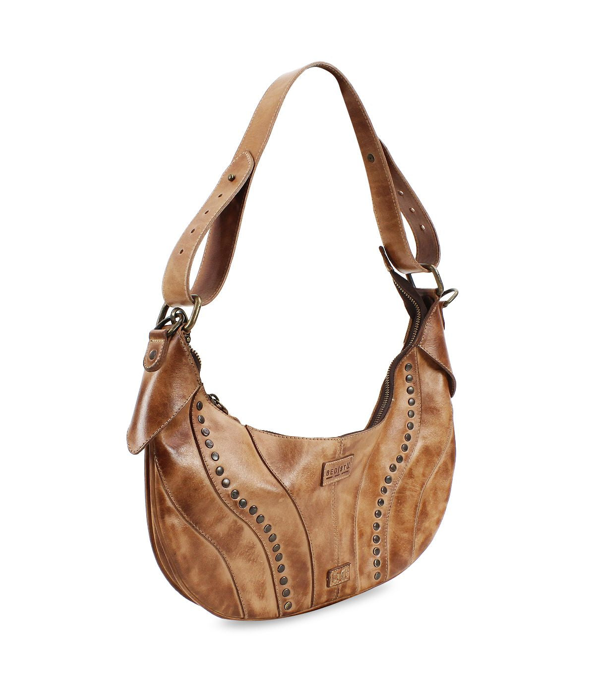 The Bed|Stü Megara is a brown leather saddle bag with decorative metal studs, an adjustable strap, and a curved design featuring refined leather details, displayed on a white background.