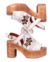 The Bed|Stü Melodramatic sandals feature a vintage-inspired platform design with chunky leather heels, embroidered floral details, white leather straps, and secure buckle closures.