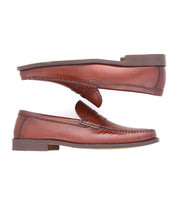 A pair of Bed|Stü Moat handcrafted leather loafers in rich brown are displayed side by side, one facing up and one facing down, against a crisp white background.