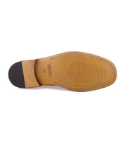 The underside of the Moat loafer by Bed|Stü, crafted from tan Italian leather, showcases a black heel, visible stitching, and horizontal grooves across the forefoot.
