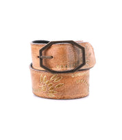 Bed|Stü’s Mohawk belt features rich brown distressed leather, eye-catching floral embroidery, and a distinctive hexagonal metal buckle—rolled up on a white background, it's perfect for adding a touch of western-inspired style to any outfit.