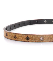 The Monae II from Bed|Stü is a brown floral cutout belt featuring small, intricate patterns and a black inner lining, shown here in a coiled display. This versatile women’s accessory adds a stylish touch to any outfit.