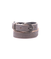 The Monae by Bed|Stü is a slim, dark brown leather belt featuring a classic silver metal buckle, elegantly coiled in a circle on a white background—an essential addition to any everyday wardrobe.