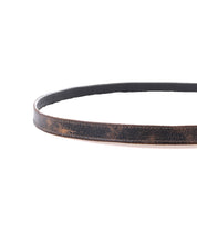 The Bed|Stü Monae is a brown leather belt with visible creases, featuring a timeless buckle, displayed in a circular shape on a white background.
