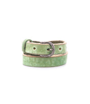 The Bed|Stü Monae belt, crafted from slim light green leather and finished with a classic silver buckle, is elegantly coiled against a white backdrop—an effortlessly stylish addition to any everyday wardrobe.