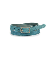 The Monae by Bed|Stü is a teal suede slim leather belt featuring a timeless rectangular silver buckle, elegantly coiled on a white background—an effortless addition to your everyday wardrobe.
