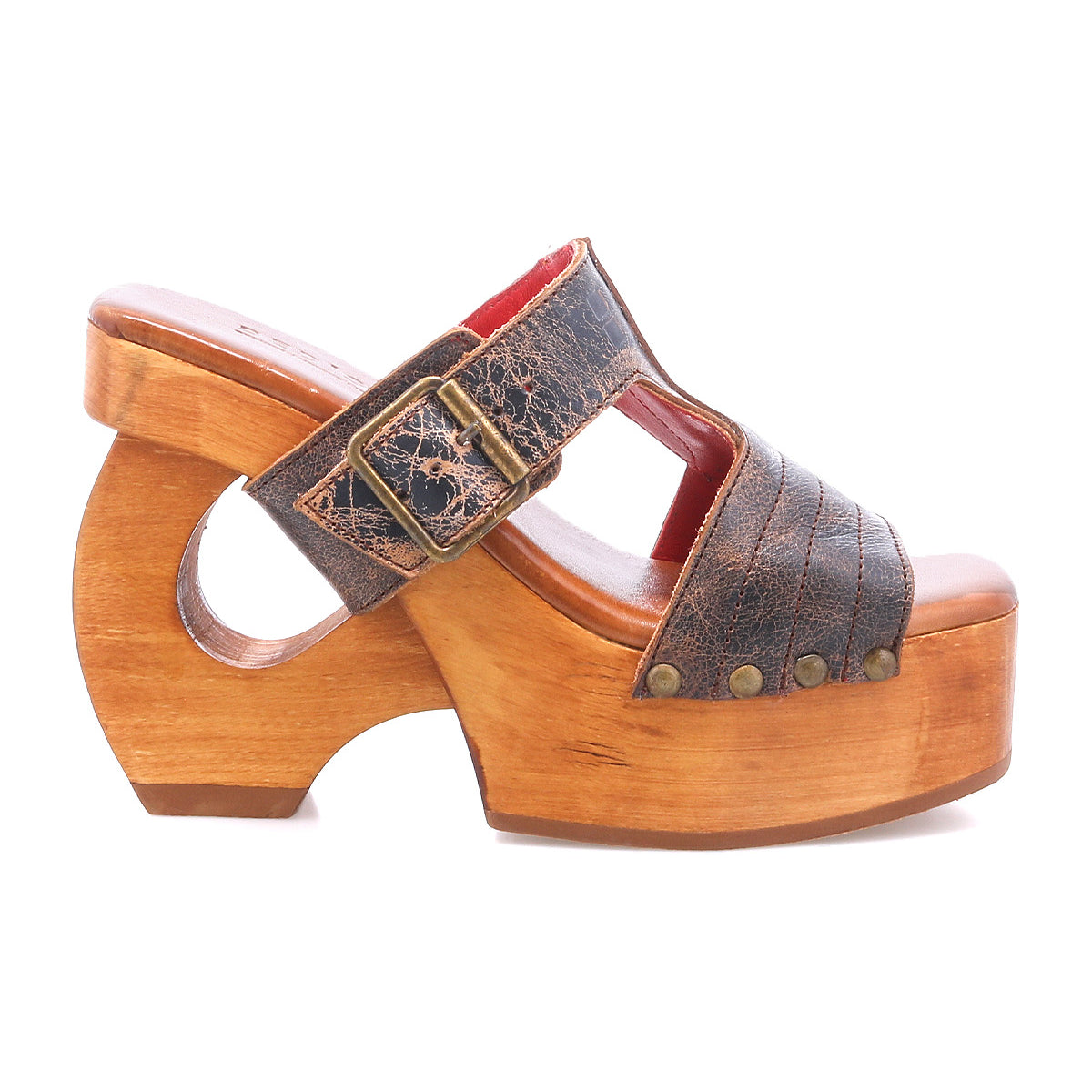The "Mutable" by Bed|Stü is a wooden platform sandal featuring a curved, vintage-inspired wooden heel, a textured brown leather strap with a decorative buckle, and metallic rivet accents.