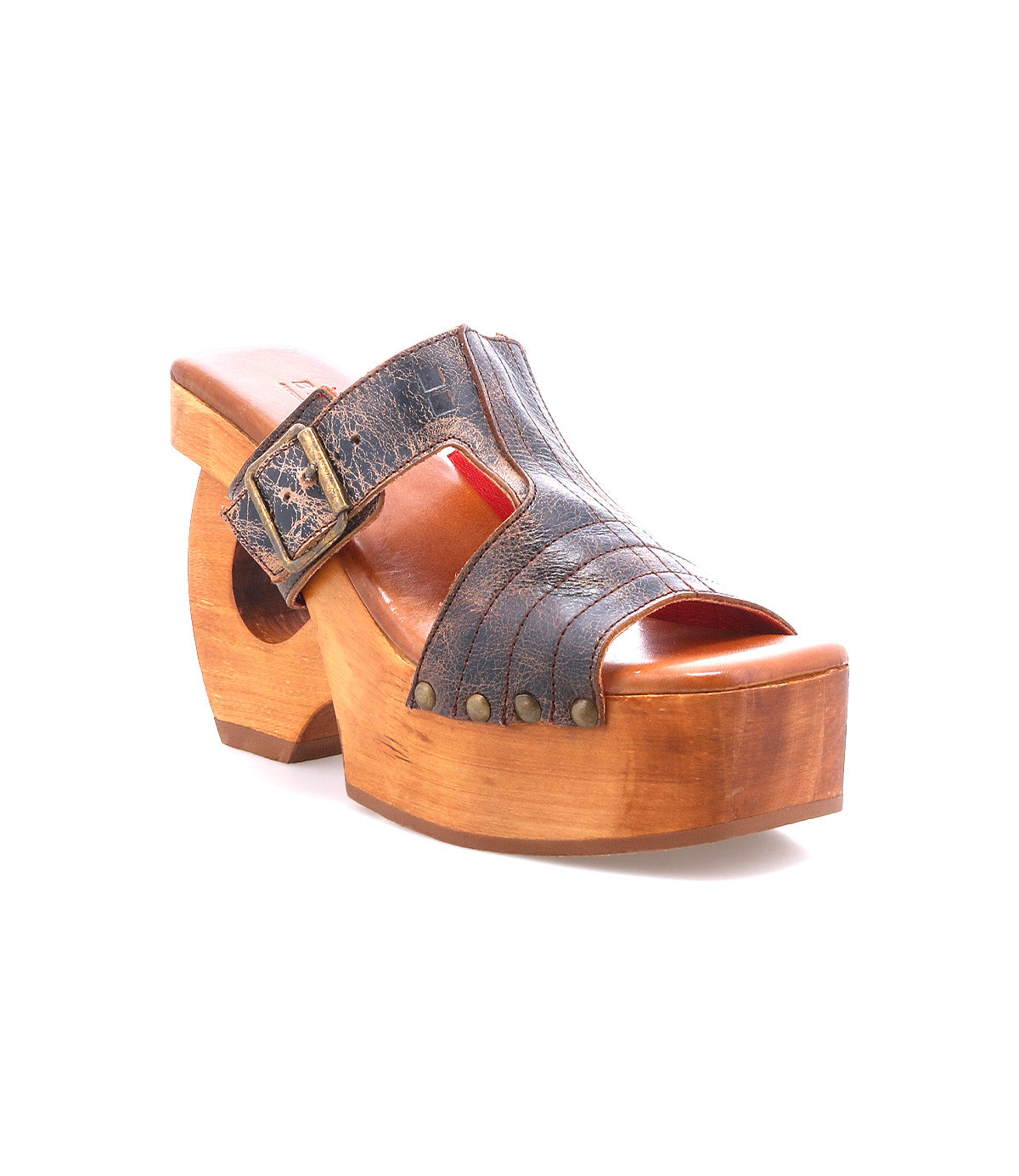 Mutable by Bed|Stü is a brown wooden platform clog with vintage influence, featuring an open toe, leather upper, decorative buckle, and metal rivets, photographed on a white background.