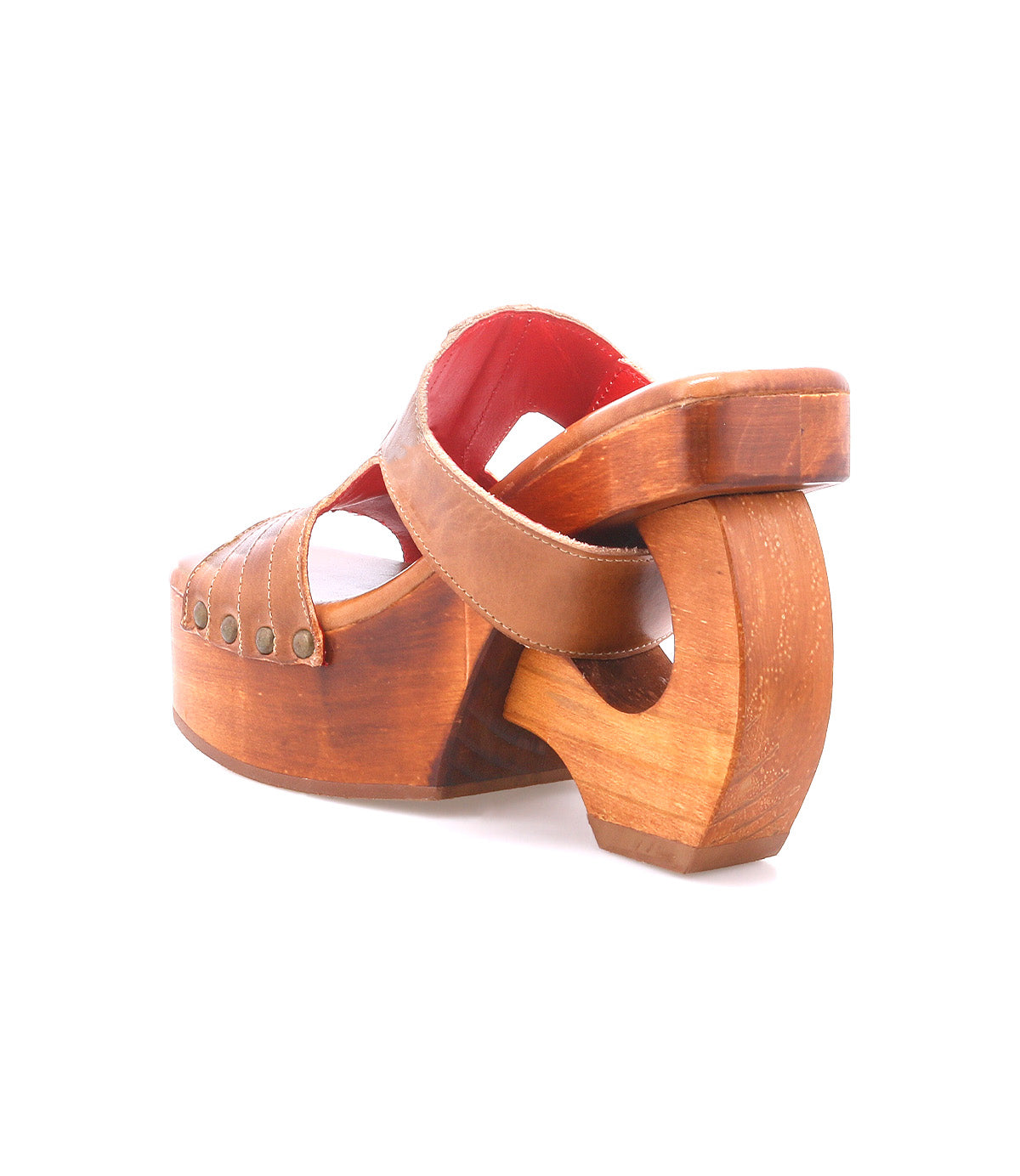 The Mutable sandal by Bed|Stü is a brown wooden platform with metal rivets and an open heel, featuring a distinctive curved cut-out in the thick sole and a decorative buckle that adds vintage flair.