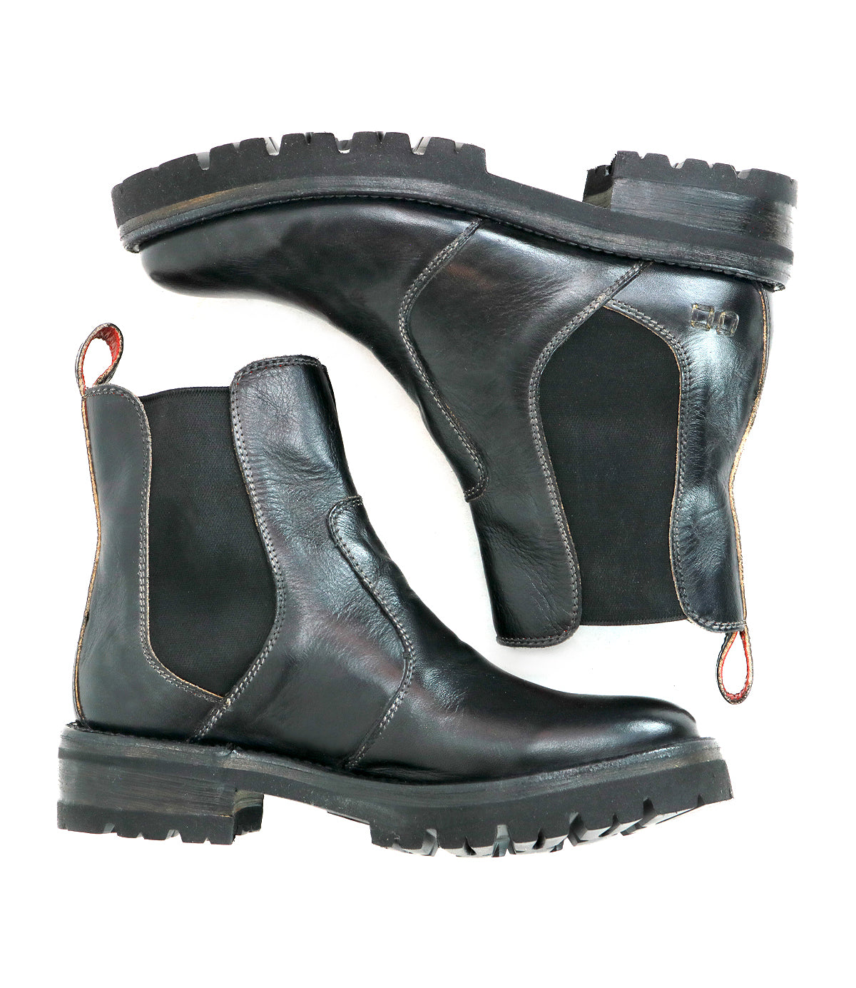 The Bed|Stü Nandi III is a pair of black leather Chelsea boots featuring dual side gores, elastic panels, pull tabs, and lug soles, displayed from the side and bottom on a white background—an effortlessly timeless boot.