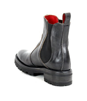 The Bed|Stü Nandi III is a black leather Chelsea boot featuring dual side gores, a rugged sole, and a distinctive red inner lining. Shown from a rear side angle on a white background, this timeless boot combines style and durability.