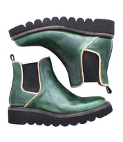 A pair of Bed|Stü Novel II green leather Chelsea boots, featuring a smooth leather upper, black elastic sides, and a thick, black scalloped platform sole, are positioned side by side—one upright and one on its side.