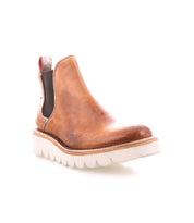 Introducing the Bed|Stü Novel II: a brown leather Chelsea boot featuring a premium leather upper, black elastic side panel, and red pull tab, set on a white ridged platform sole. Shown on a white background.